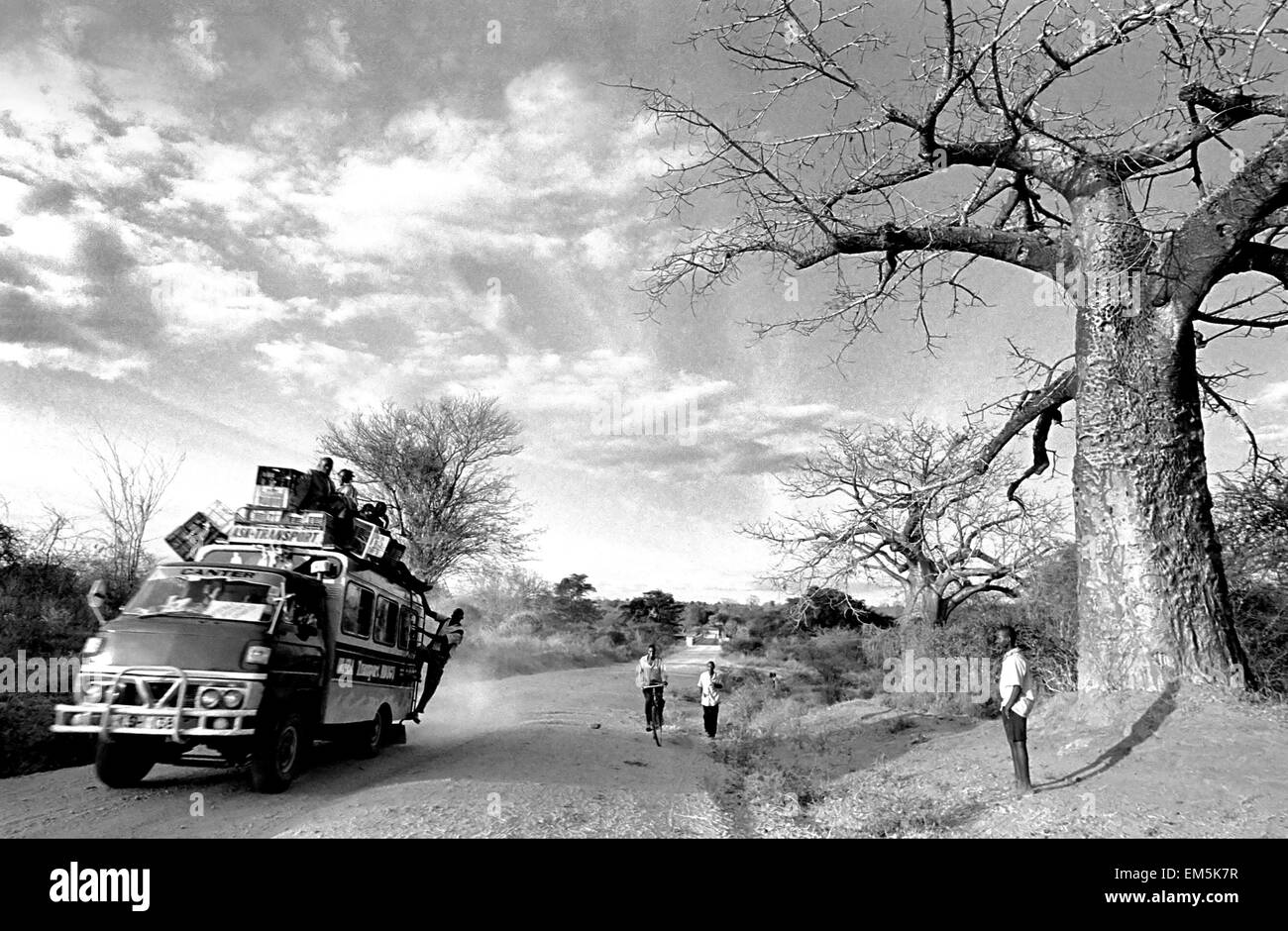 A matatu heavily loaded and a baobab in a dusty road in rural Kenya. Landscape. The infrastructure in Kenya are very poor. The r Stock Photo