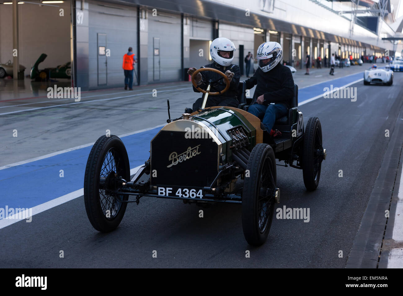 . A passenger rides in a classic 1909 Berliet  race car. A passenger was chatting to the driver in the pit lane at Silverstone, as they wait to gain access to the race track. Stock Photo