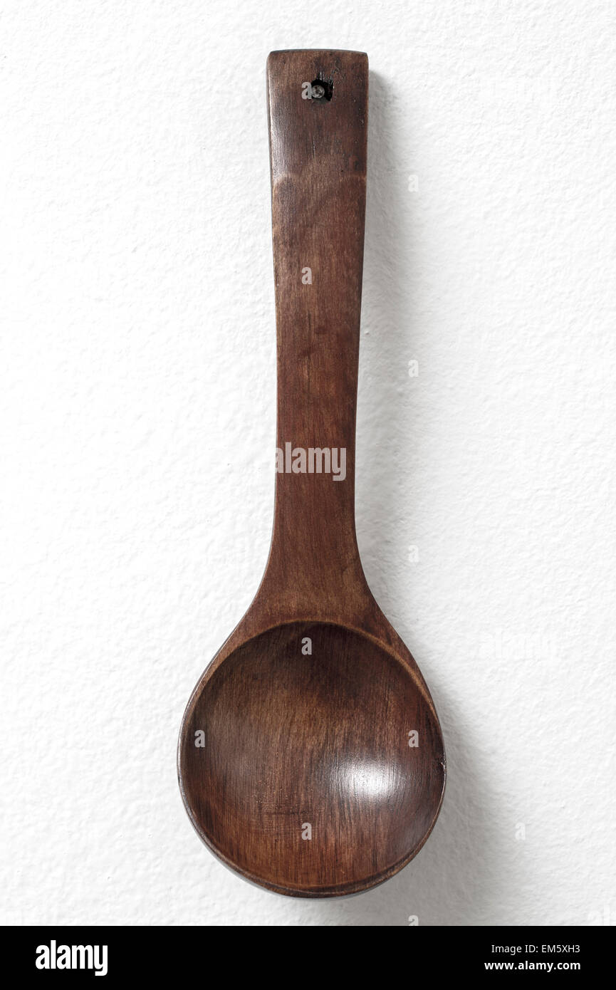 Wooden spoon hanging against white wall as a background Stock Photo - Alamy