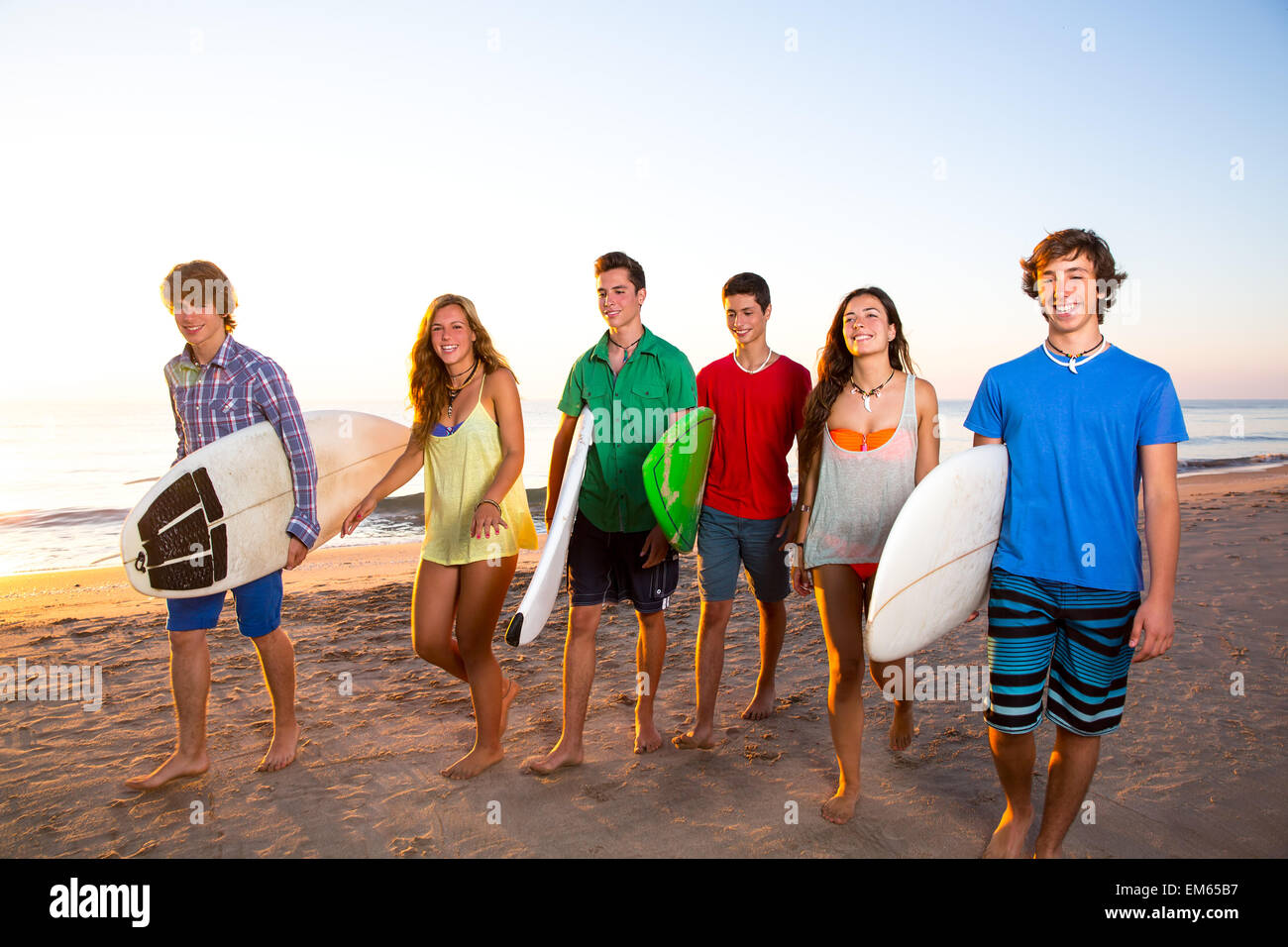 Surfer teen boys girls group walking on beach Stock Photo