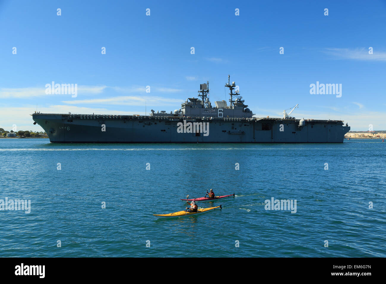 A photograph of two kayakers in front of the USS America (LHA-6), in San Diego Bay, as seen from Seaport Village. Stock Photo