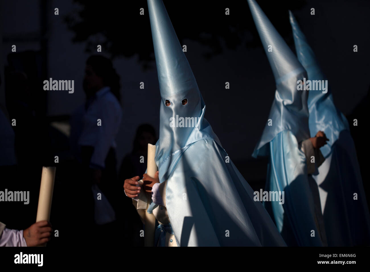 Hooded penitents holding candles participate on the procession of Palm Sunday during easter Week in Prado del Rey, Sierra de Grazalema Natural Park, Cadiz province, Andalusia, Spain Stock Photo