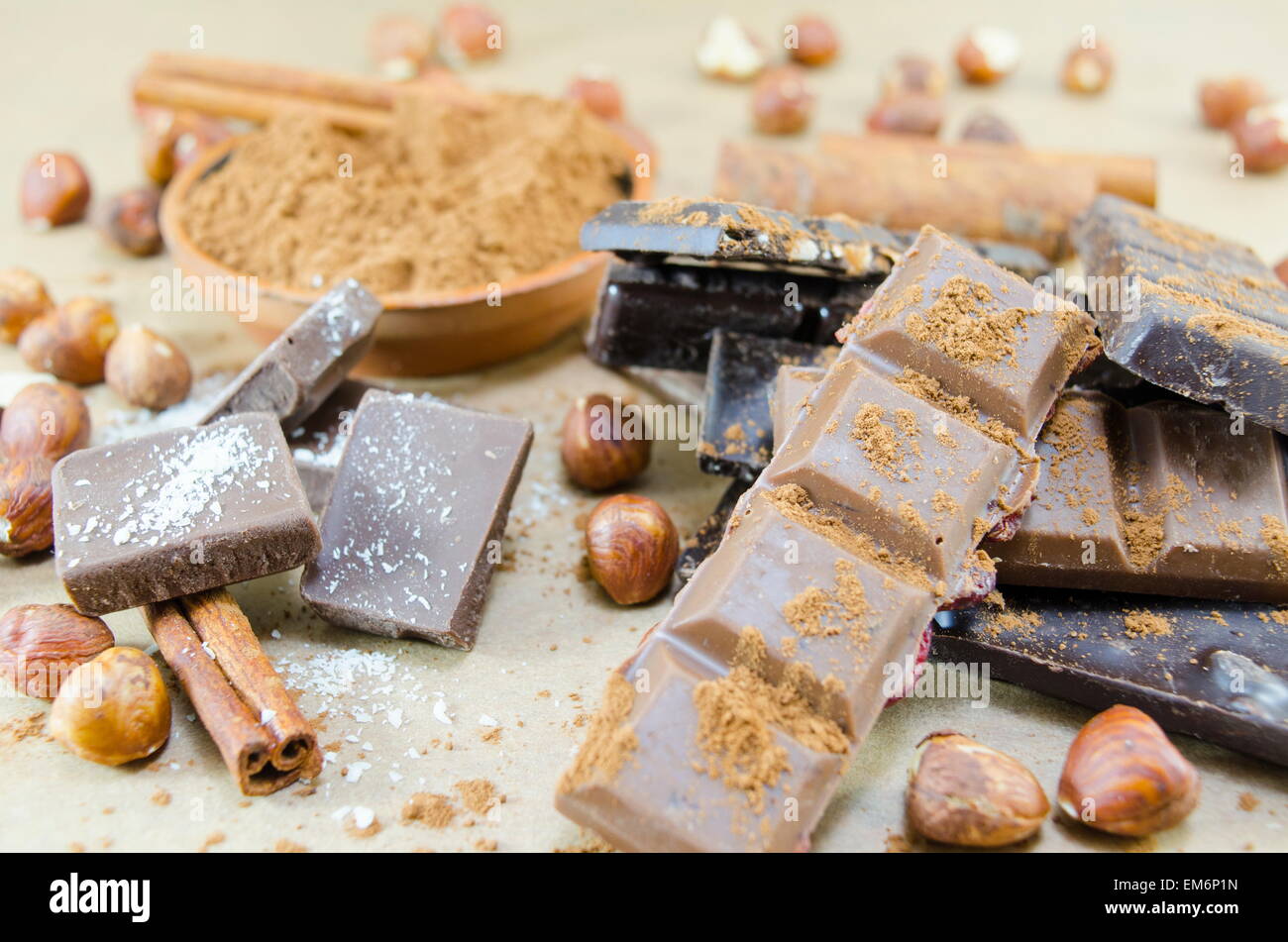 Bunch of chocolate sticks, cinnamon and hazelnuts on a table Stock Photo