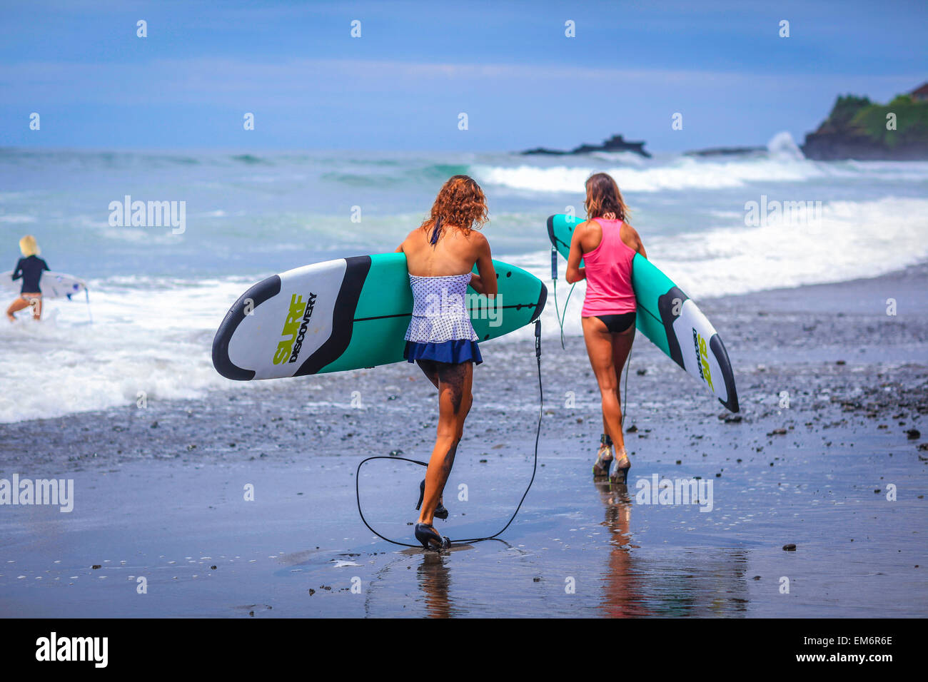 Surfer girls catch waves in high heels. Stock Photo