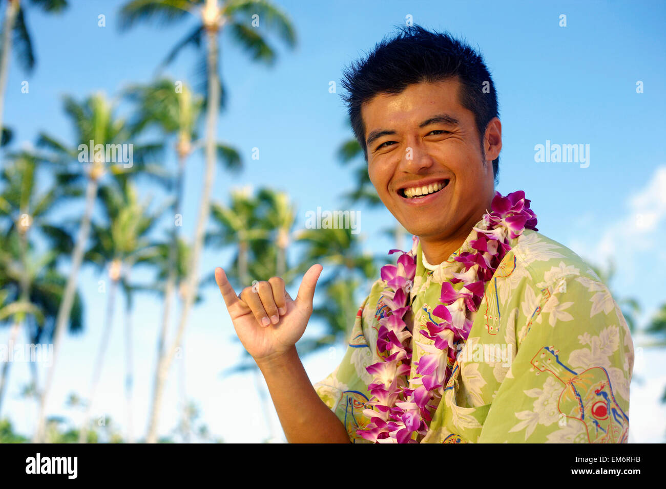 Hawaii, Oahu, Japanese Man Wearing Lei Making Shaka Sign, Palm Trees In