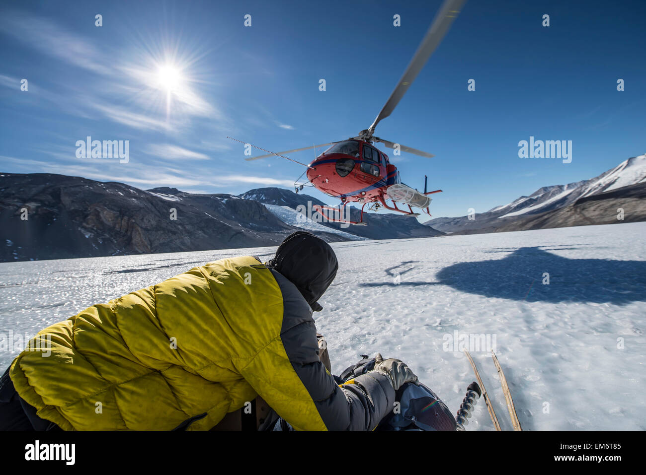 A scientist holds equipment while a helicopter lands next to him on the Taylor Glacier, Antarctica. Stock Photo