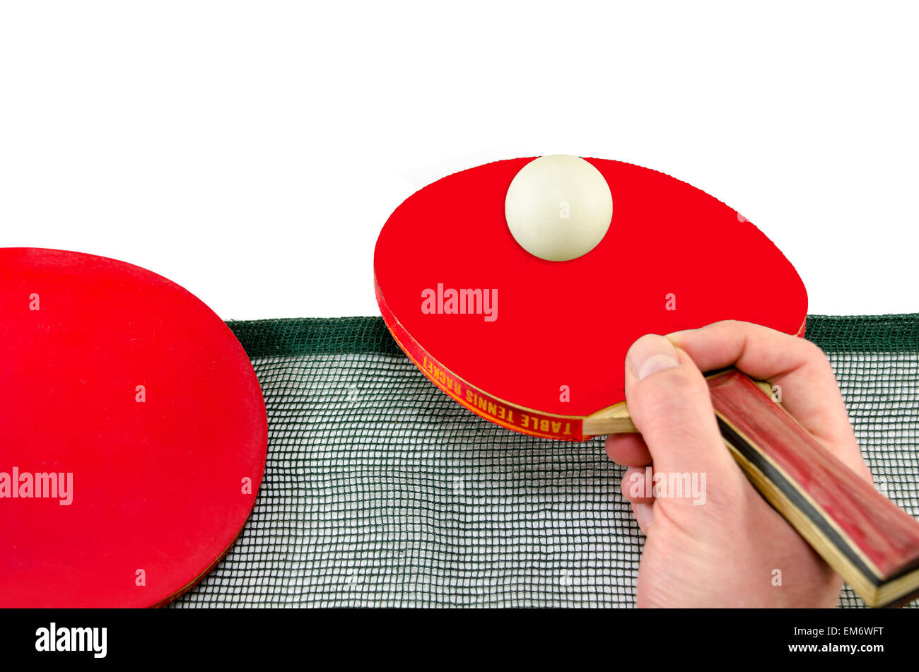 Male hand holding a ping pong racket and a table tennis ball above a net, isolated on white Stock Photo