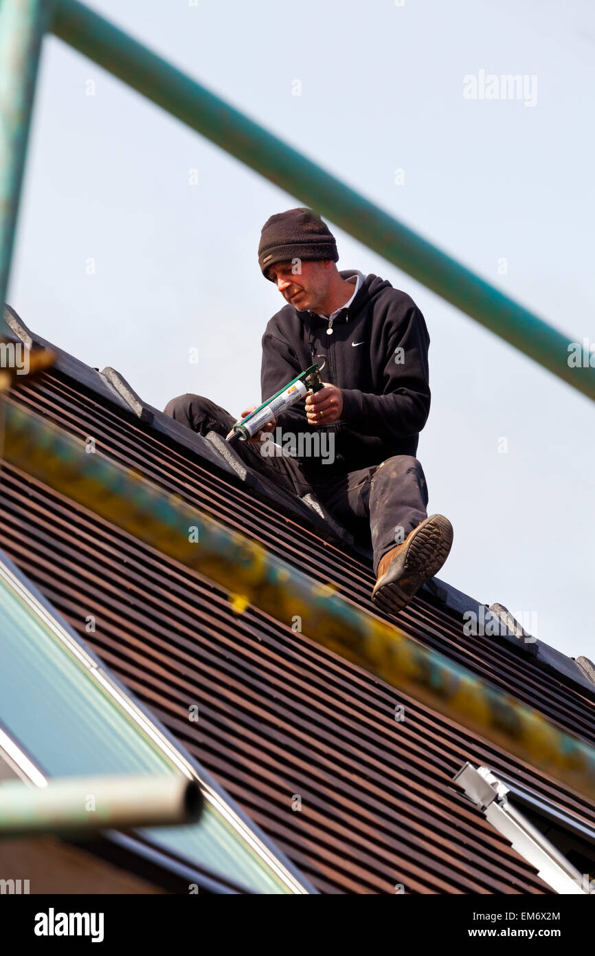 Construction worker securing roof tiles on a building site with ...