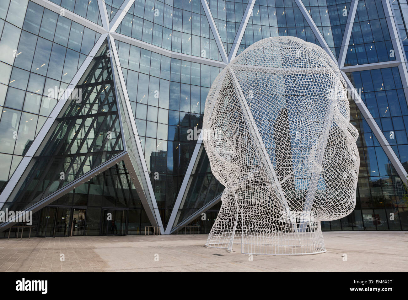 Sculpture of a human head in front of a modern building of windows