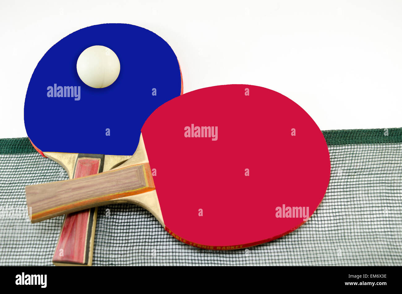 Two table tennis rackets one on top of the other and an old net isolated on white. One paddle is red and the other is black Stock Photo