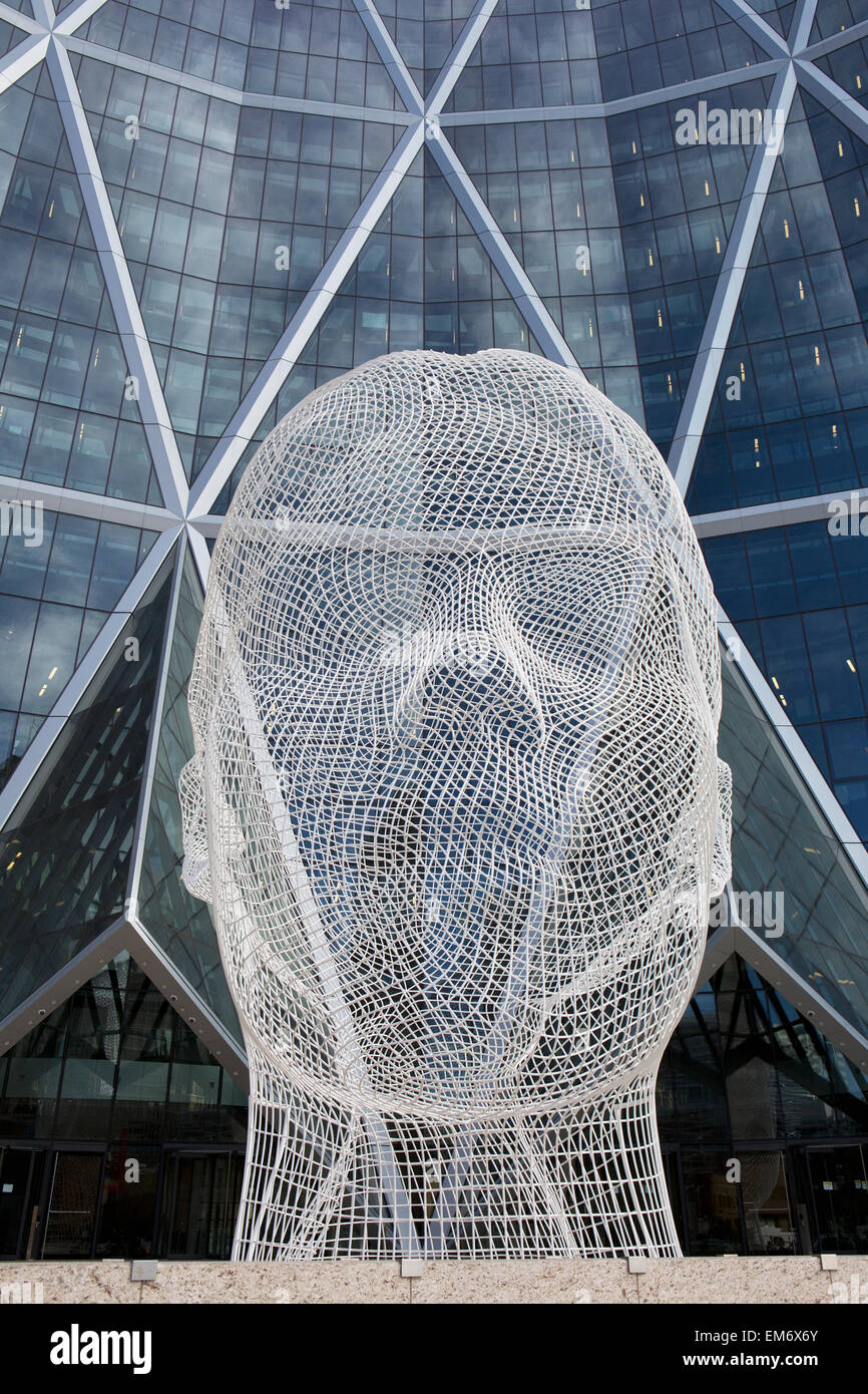 Sculpture of a human head in front of a modern building of windows