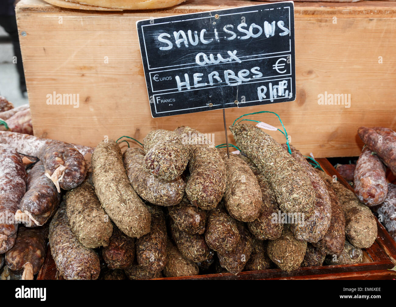 Herb pork sausage salami meat for sale at a French market.  The herb covered sausages are hand made and air dried. Stock Photo
