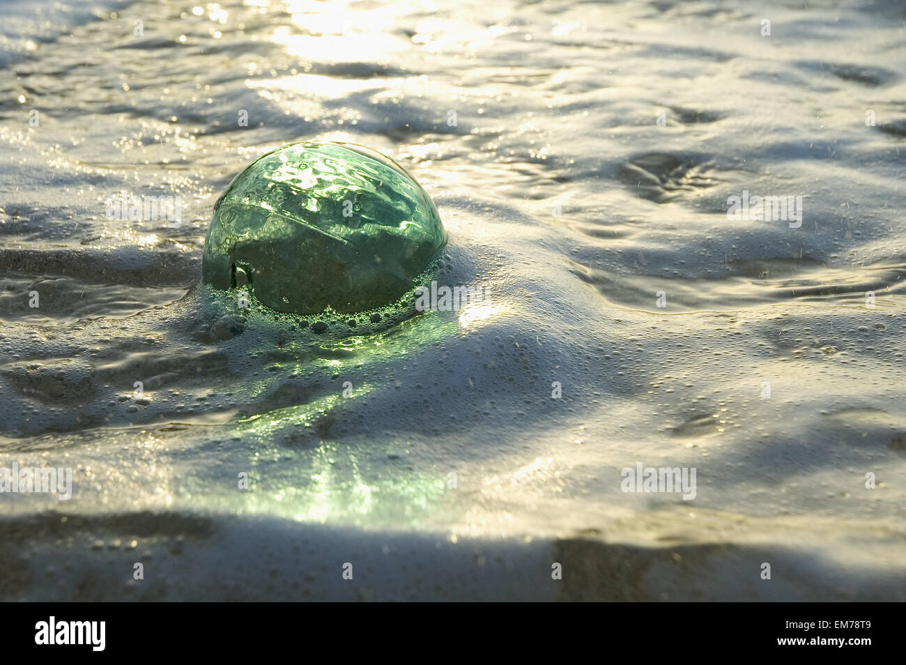 A Glass Fishing Ball Floats In Shallow Water, Bright Reflections