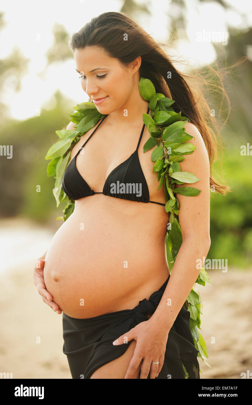 Pregnant Girl Wearing Black Bikini And Green Leaf Lei, Holding Tummy Stock  Photo - Alamy