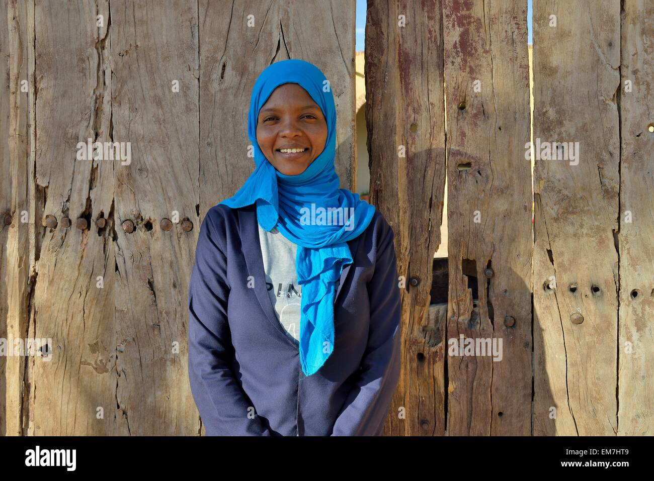 Young woman with headdress, against a wooden door, portrait, Karima, Northern, Nubia, Sudan Stock Photo