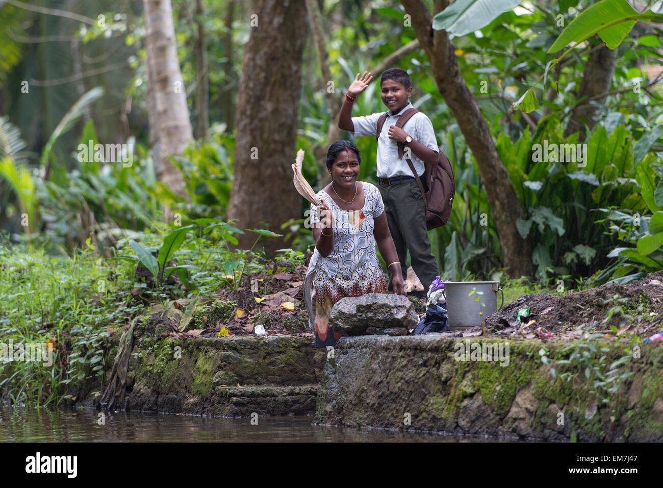 Woman and child waving, Backwaters canal system in Alappuzha, Kerala, India Stock Photo
