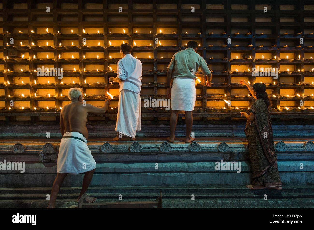 Oil lamps being lit in niches on the outer wall of the temple for the Hindu fire ceremony Aarti, Ambalapuzha, Kerala, India Stock Photo