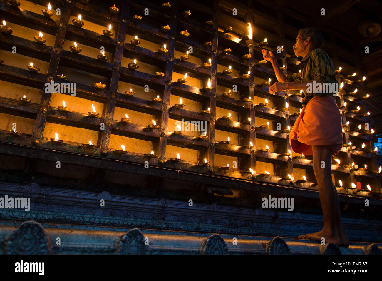 Man lighting an oil lamp, outer wall of the temple, Hindu fire ceremony Aarti, Ambalapuzha, Kerala, India Stock Photo