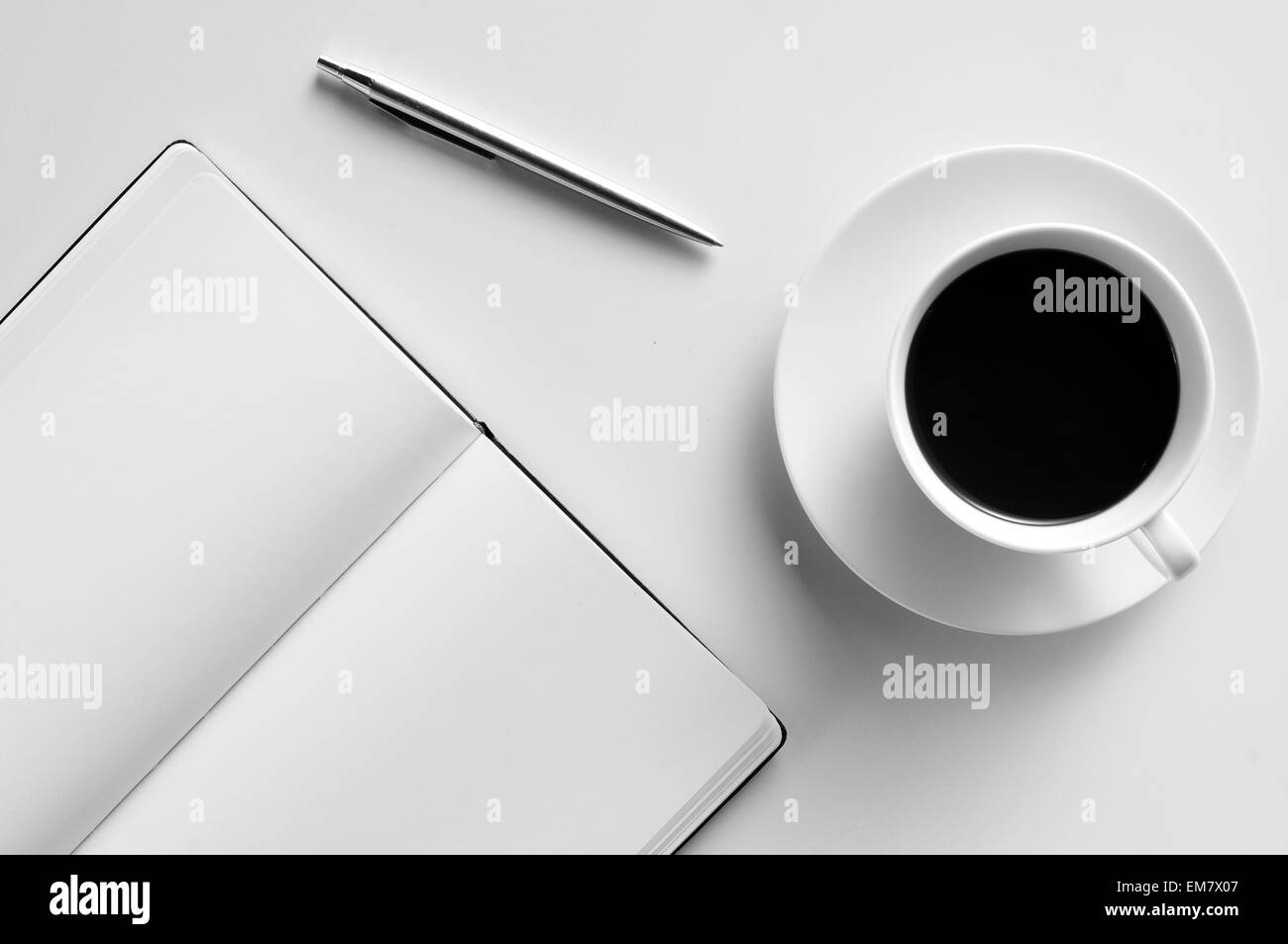 high-angle shot of a blank notepad, a pen and a cup of coffee on a white table Stock Photo