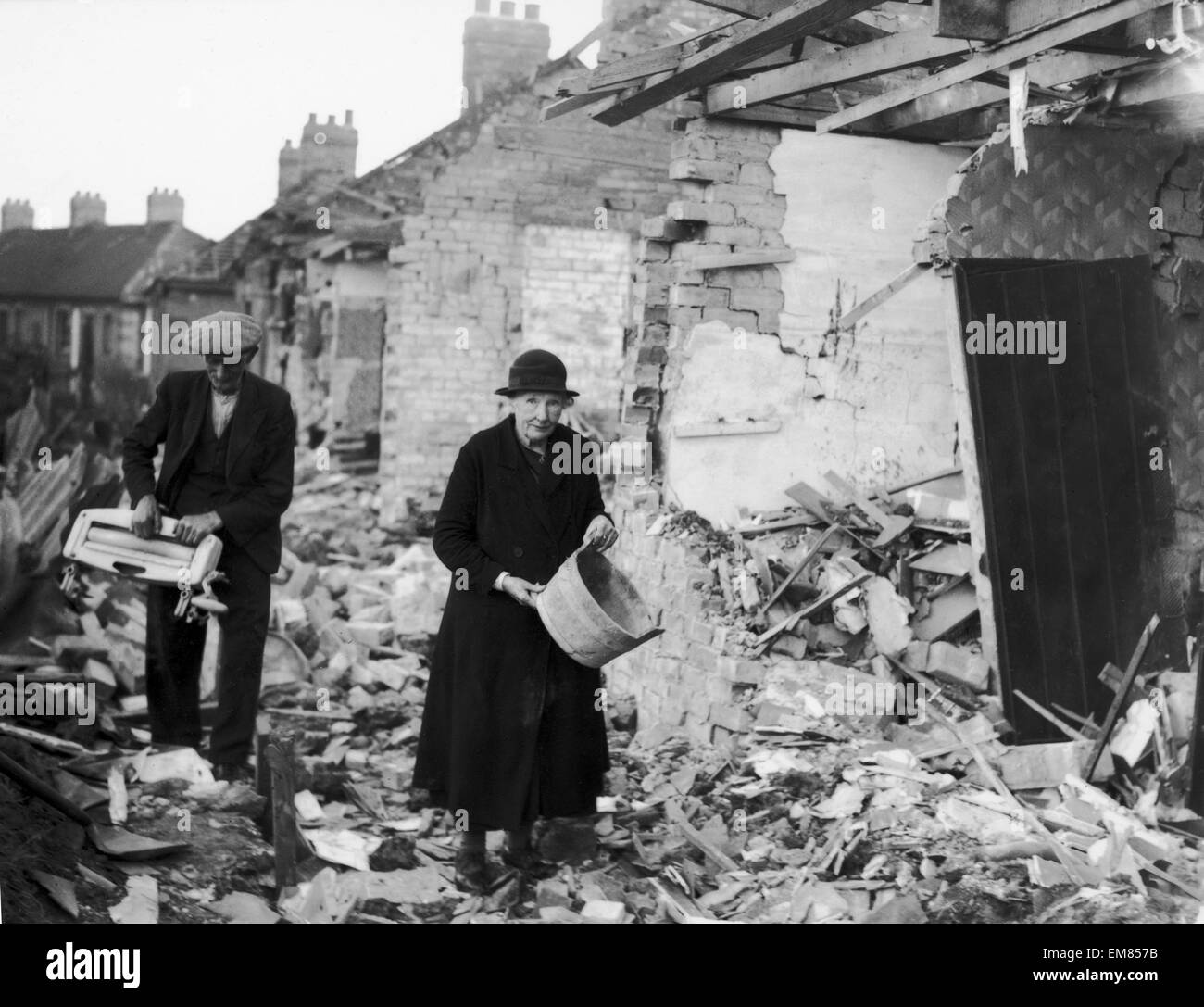 An elderly couple clear away the rubble near their homes after an air raid by the German Luftwaffe on a residential area of Newcastle in World War Two. Circa 1940. Stock Photo