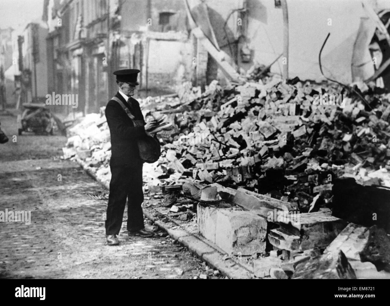 Smithford Street looking towards Fleet Street in Coventry after an air raid by the German Luftwaffe in World Wat Two. St. John's church can just be made out on the top left of the photo. This postman is struggling to decide what to do with the mail for businesses that were raized to the ground during the Coventry blitz of 14th November 1940. Stock Photo
