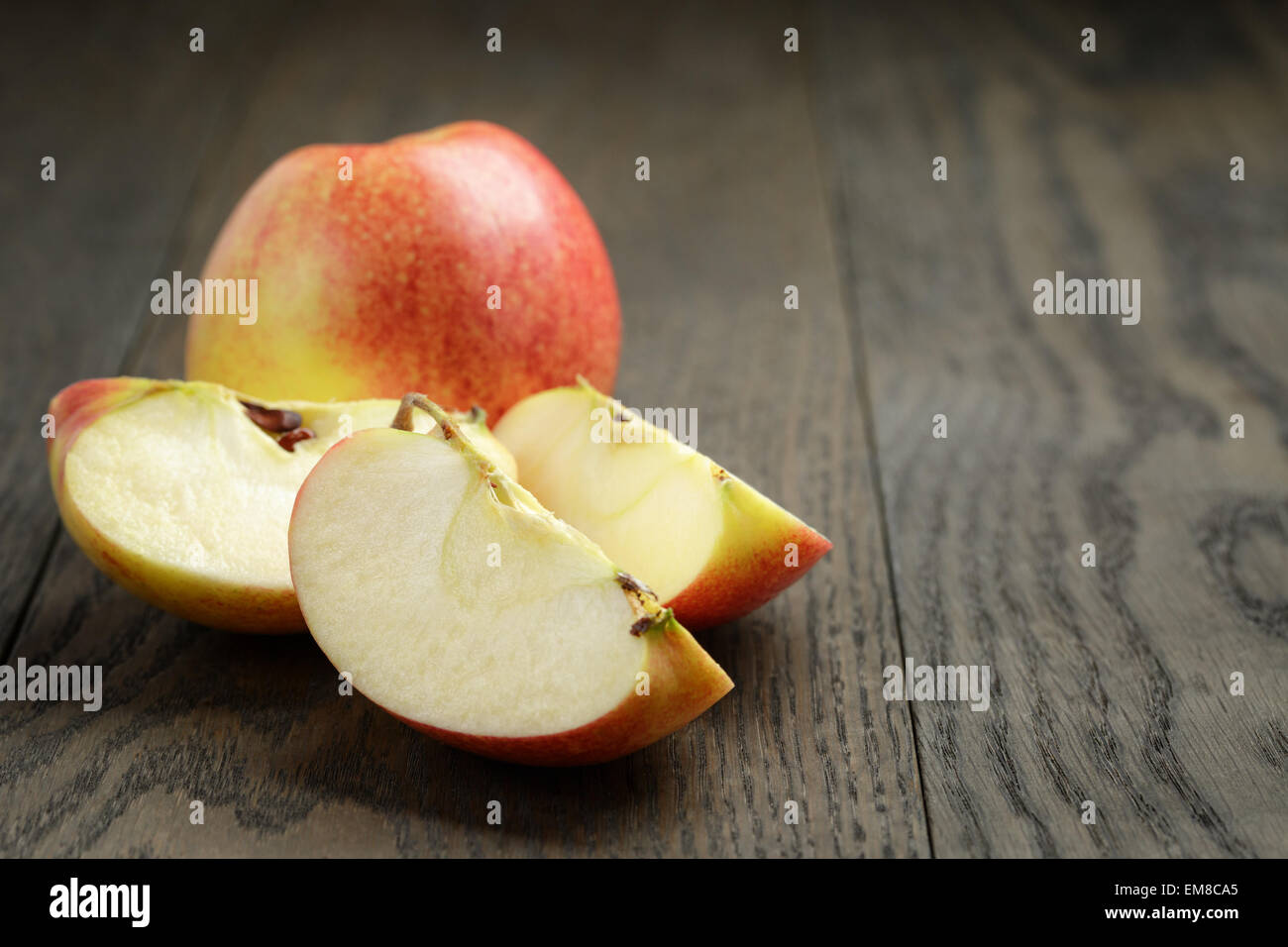 seasonal red apples sliced on wooden table Stock Photo