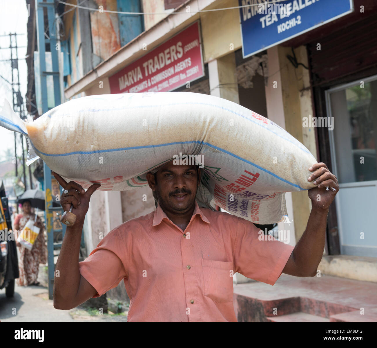 A man carrying a heavy bag of rice on his head in Fort Kochi, Kerala India Stock Photo
