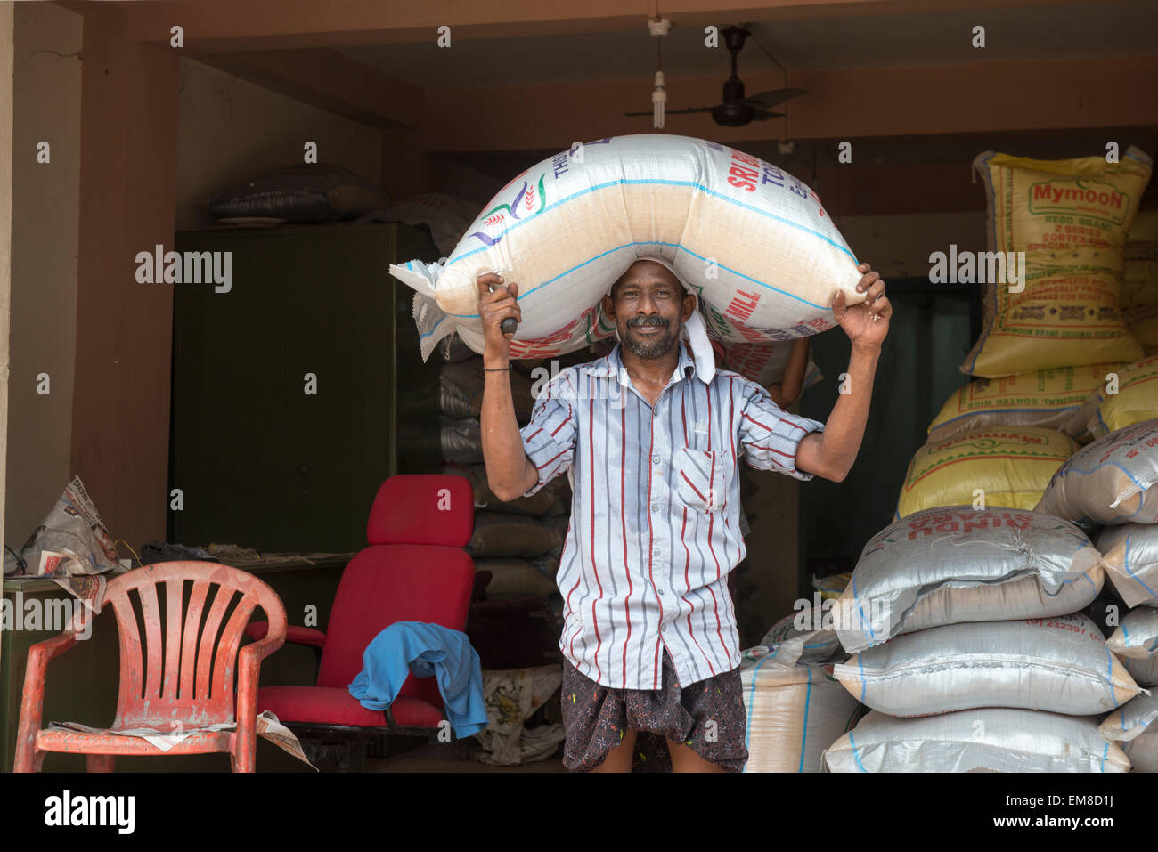 A man carrying a heavy bag of rice on his head in Fort Kochi, Kerala India Stock Photo