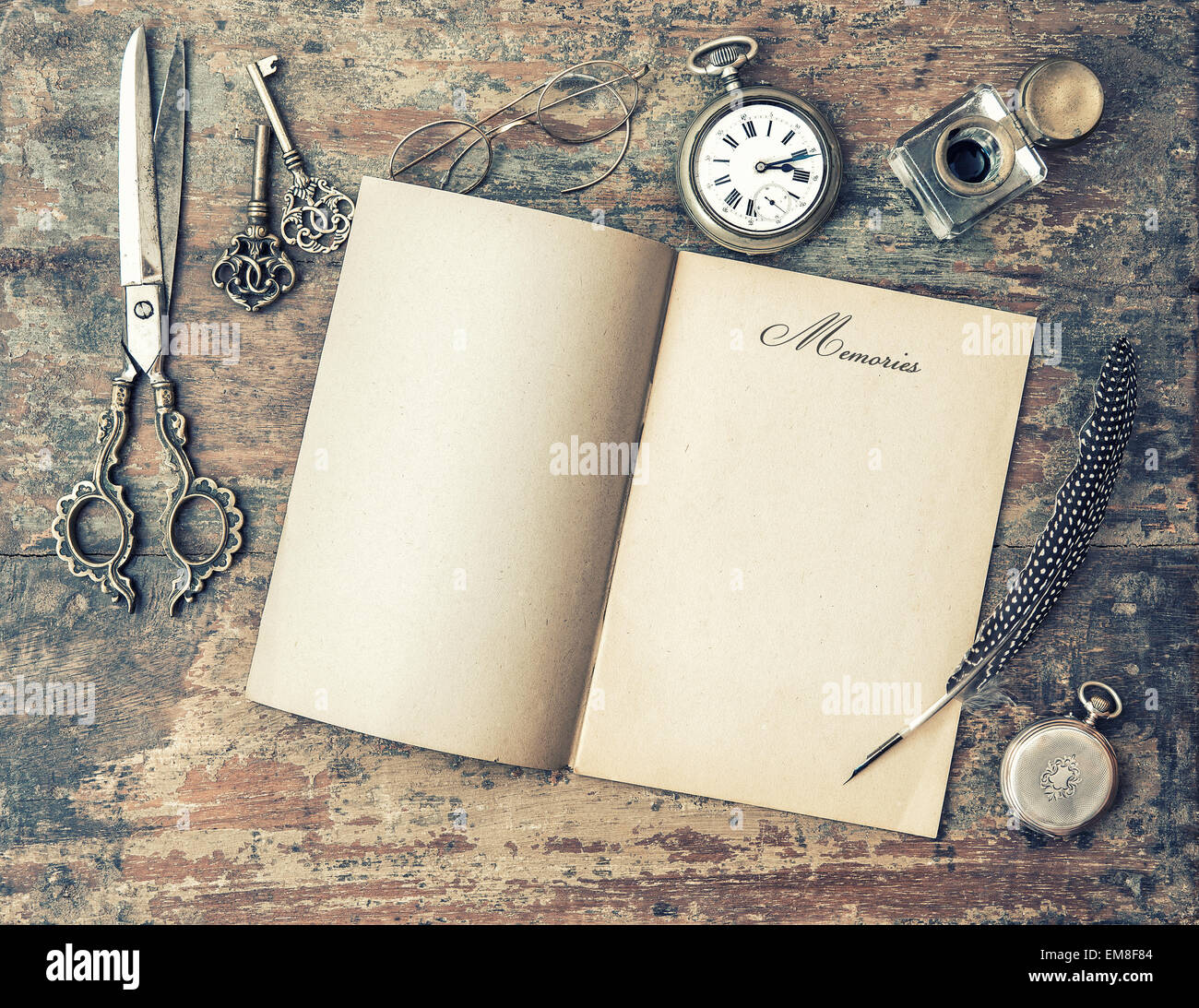 Open journal book and vintage writing tools. Feather pen, inkwell, keys on textured wooden background. Memories. Stock Photo