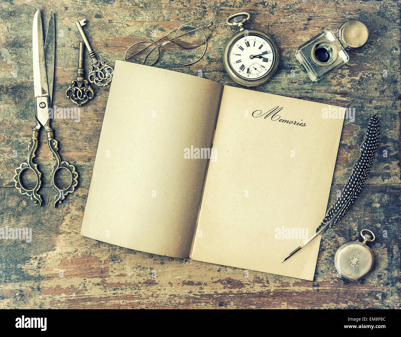 Paper page and vintage writing tools. Feather pen, inkwell, keys on textured wooden background. Stock Photo