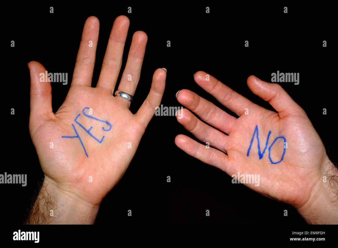 Two white hands with the words "yes" and "no" written on them against a black background. Stock Photo