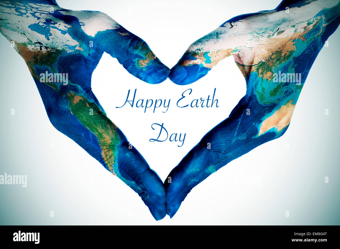 the hands of a young woman forming a heart patterned with a world map (furnished by NASA) and the text happy earth day Stock Photo