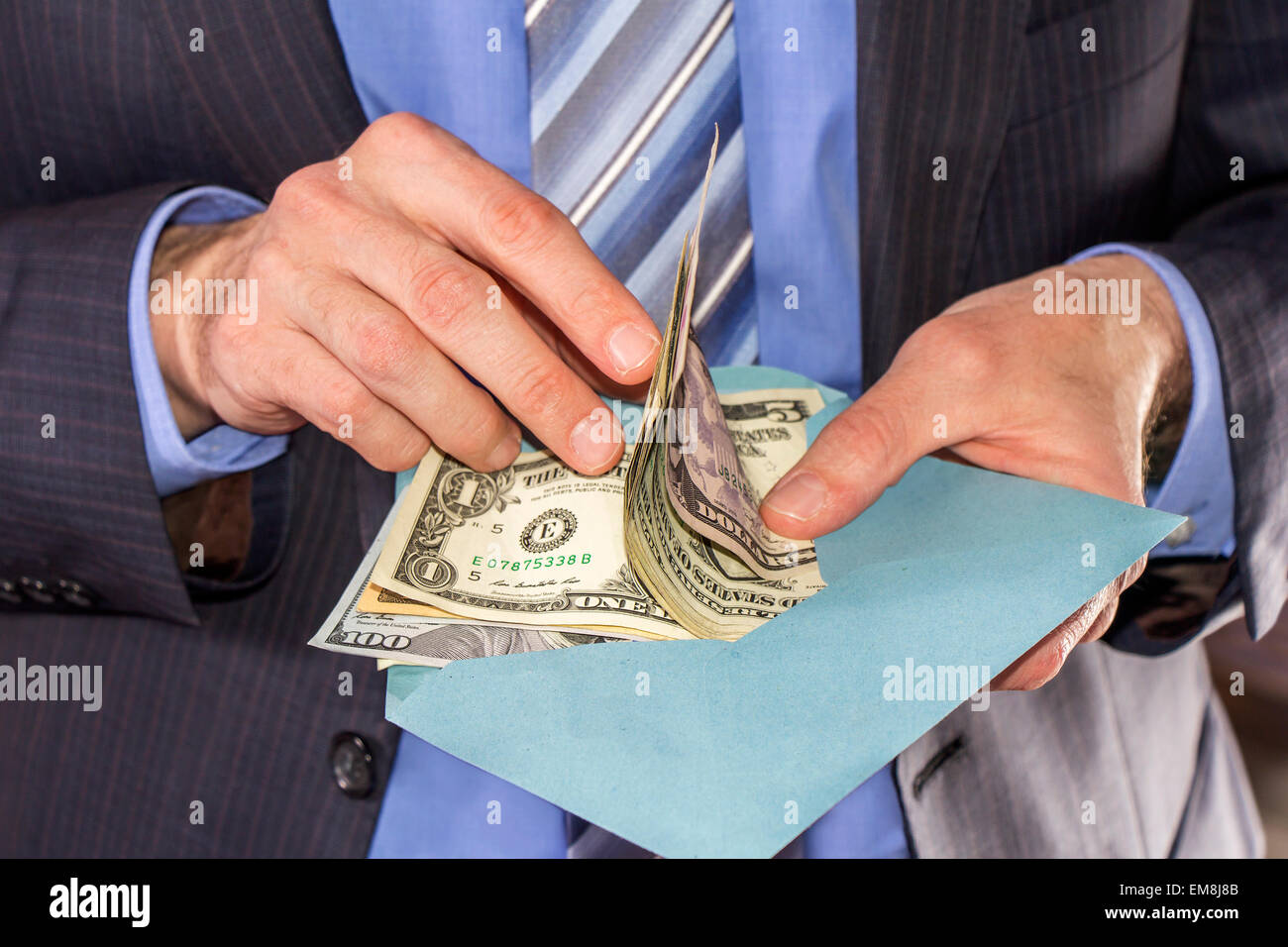 Businessman counting dollars bribe in a blue envelope Stock Photo
