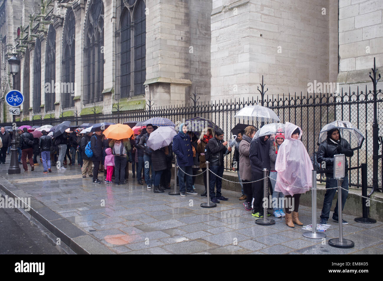 Tourists queue in the rain to see the Notre Dame cathedral in Paris Stock Photo