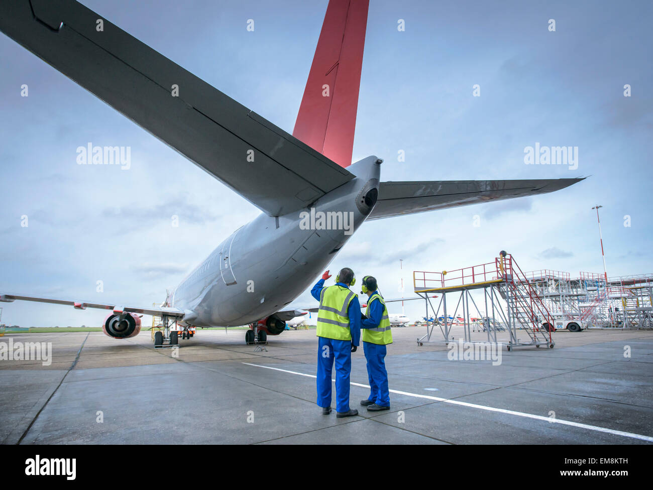 Airside engineers inspecting jet aircraft on runway Stock Photo