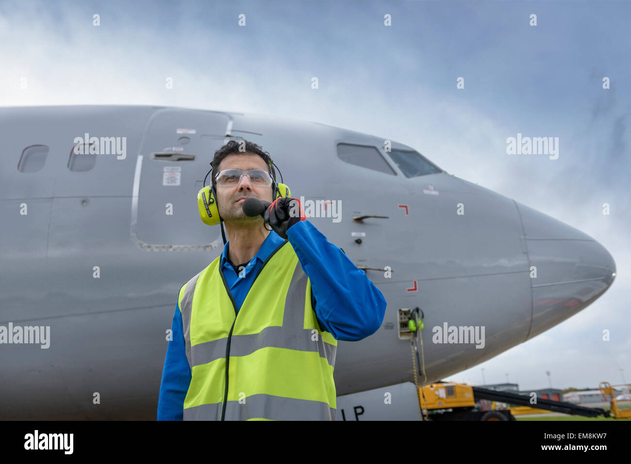 Airside engineer talking on radio near aircraft on runway, low angle view Stock Photo