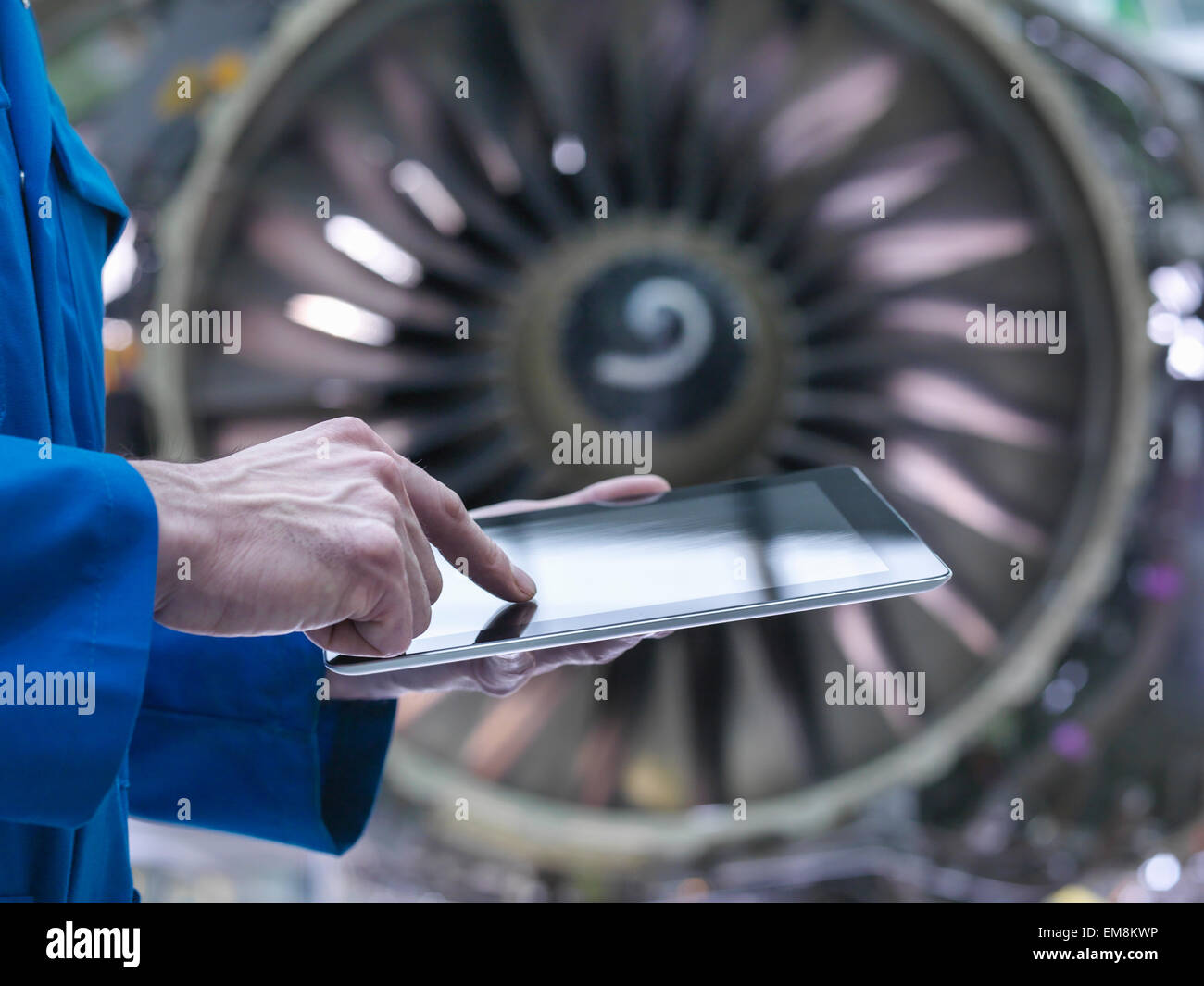 Engineer using digital tablet in front of jet engine in aircraft maintenance factory Stock Photo