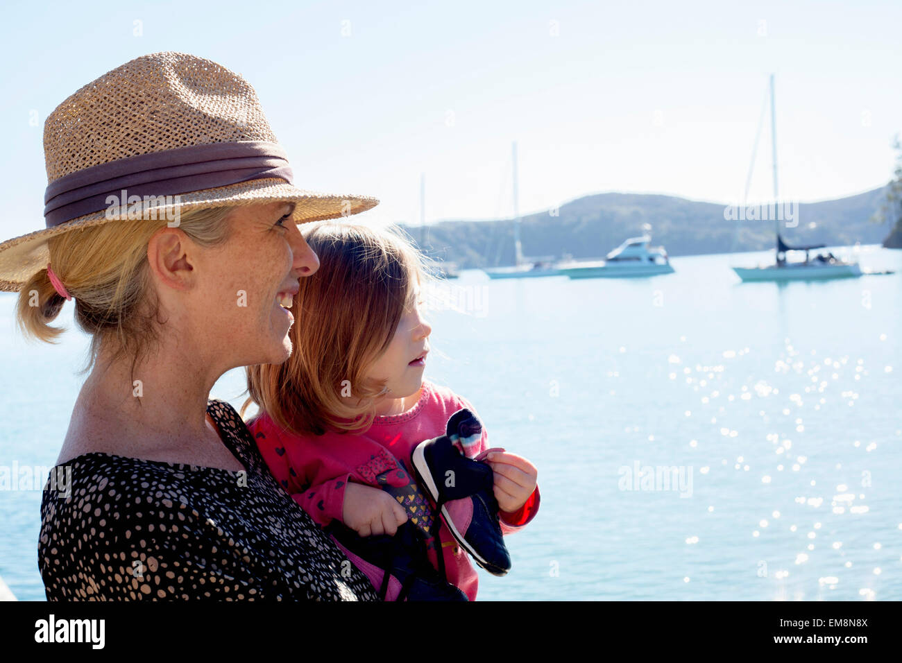 Portrait of mid adult woman and toddler daughter at coast, New Zealand Stock Photo