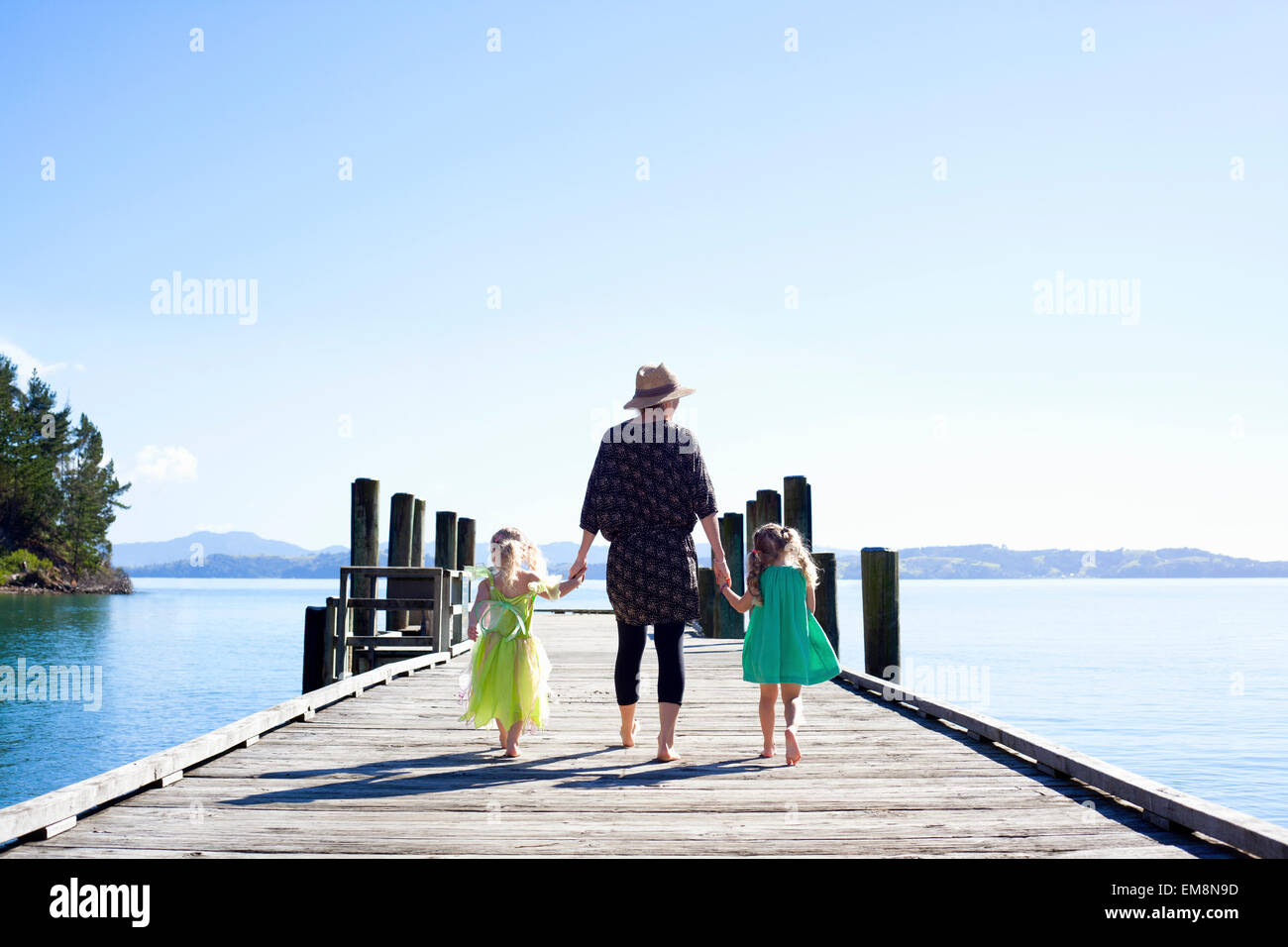 Mid adult woman and daughters strolling on pier, New Zealand Stock Photo