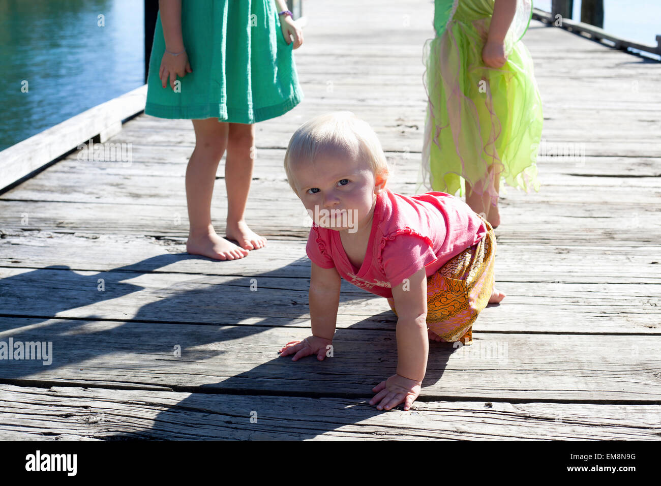 Portrait of female toddler crawling on pier, New Zealand Stock Photo