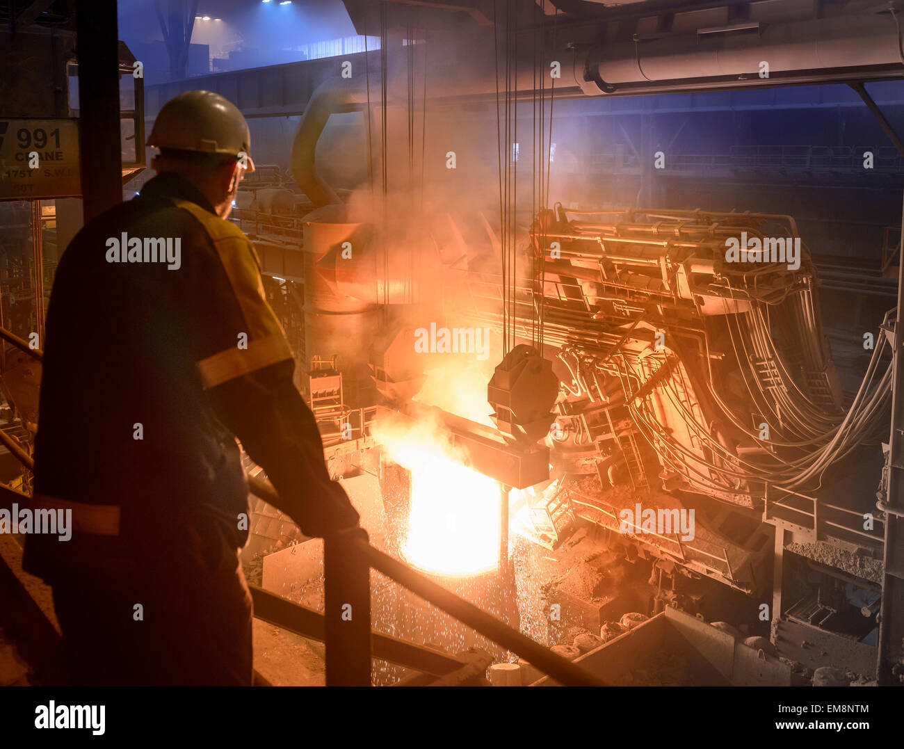 Steel worker inspecting pouring molten steel Stock Photo
