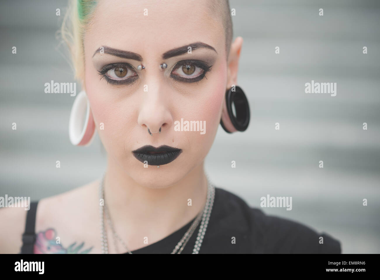 Portrait of young female punk with nose and earlobe piercings Stock Photo