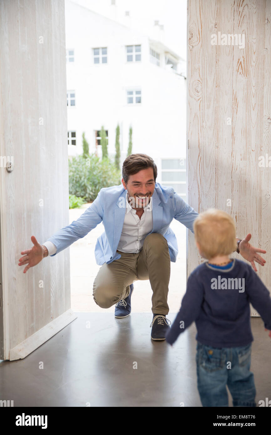 Male toddler running to fathers arms at front door Stock Photo