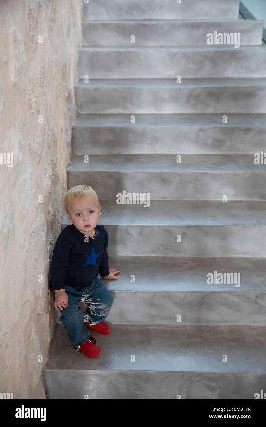 Portrait of male toddler sitting on house staircase Stock Photo