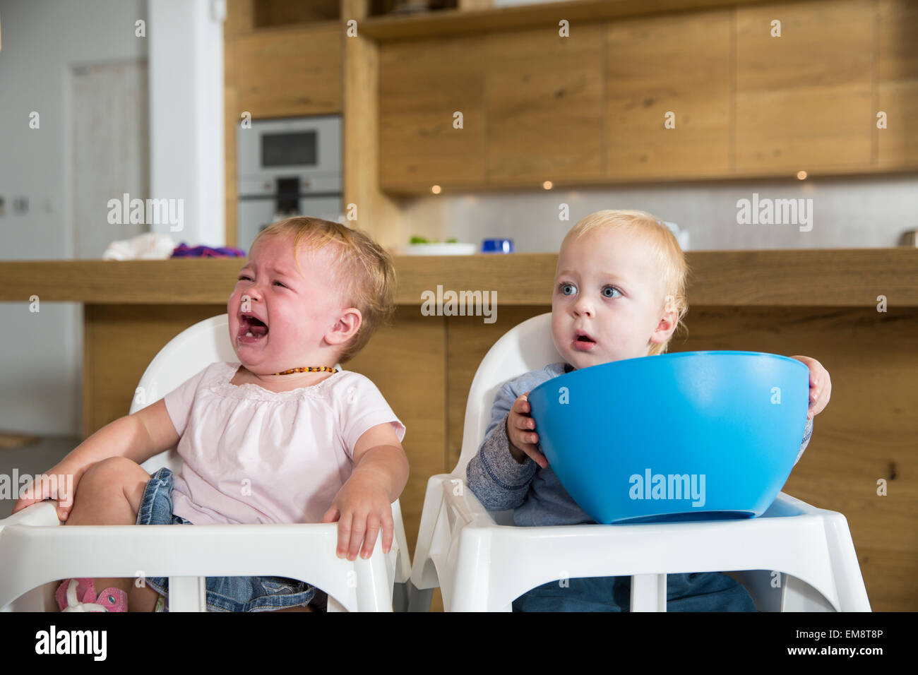 Male and female twin toddlers in high chairs Stock Photo