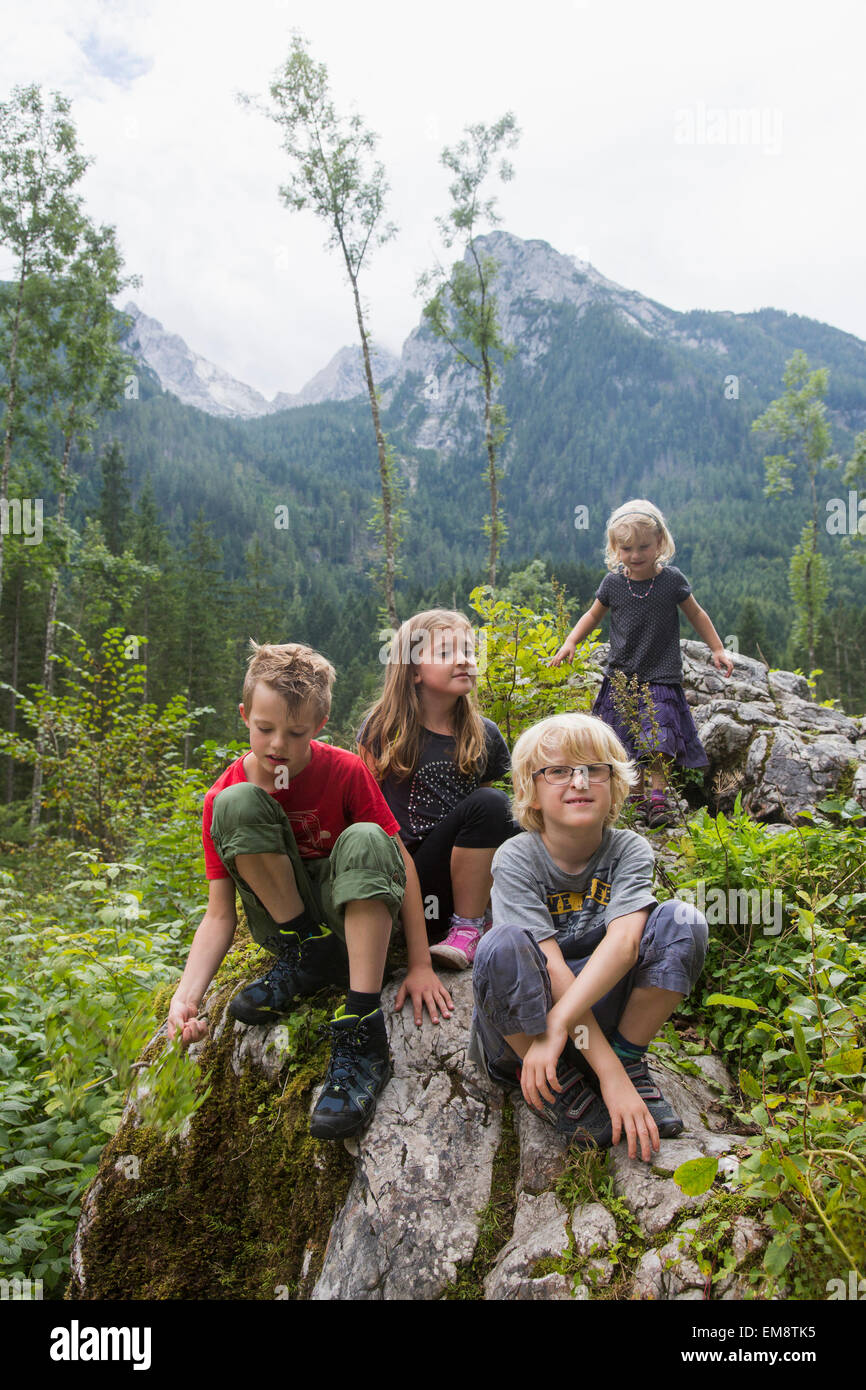 Brothers and sisters sitting on rock formation in forest, Zauberwald, Bavaria, Germany Stock Photo