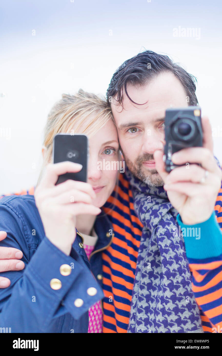 Couple taking photographs with smartphone and camera Stock Photo