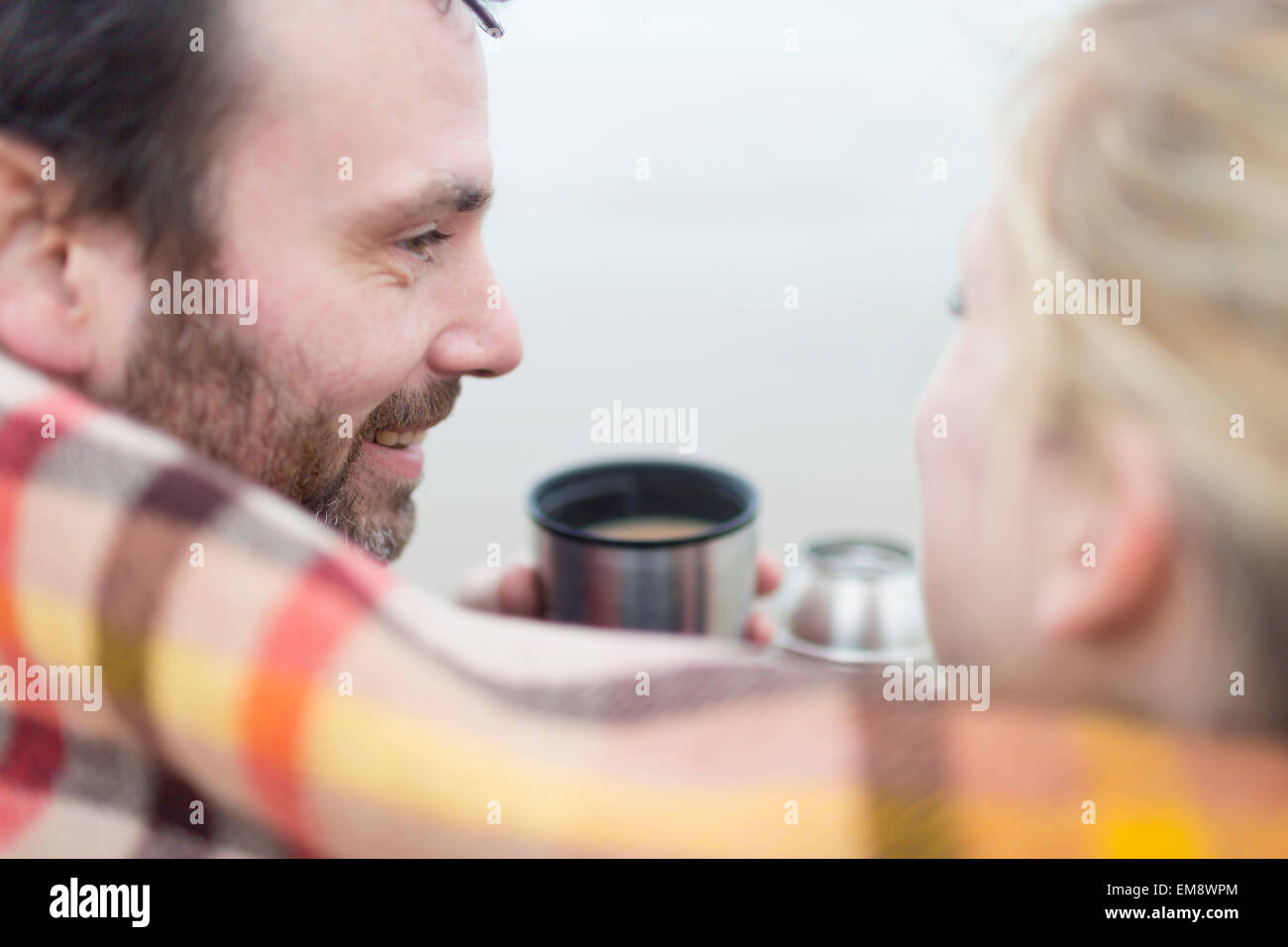Couple on beach, drinking hot drink from drinks flask Stock Photo