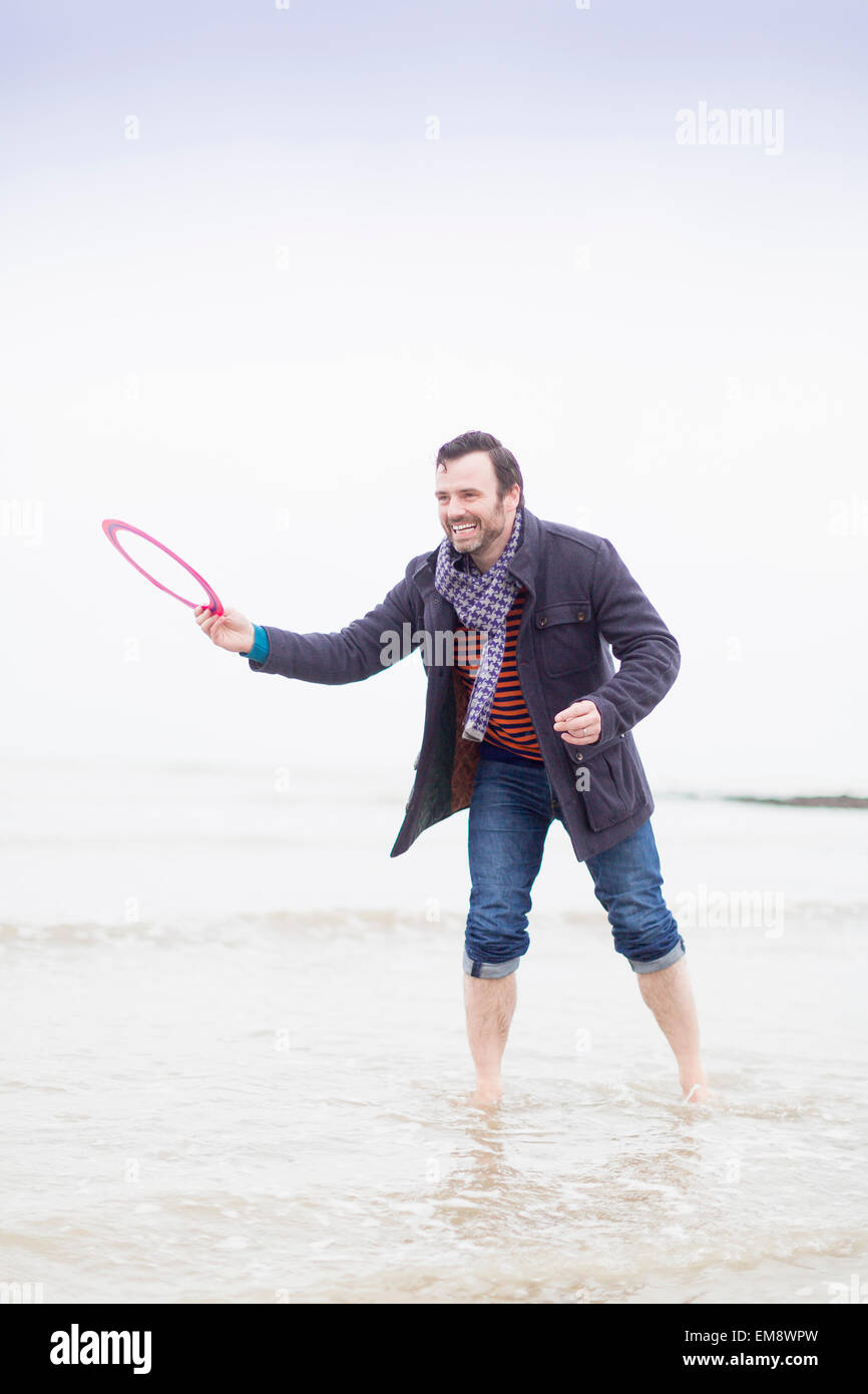 Mature man standing in sea, holding frisbee Stock Photo