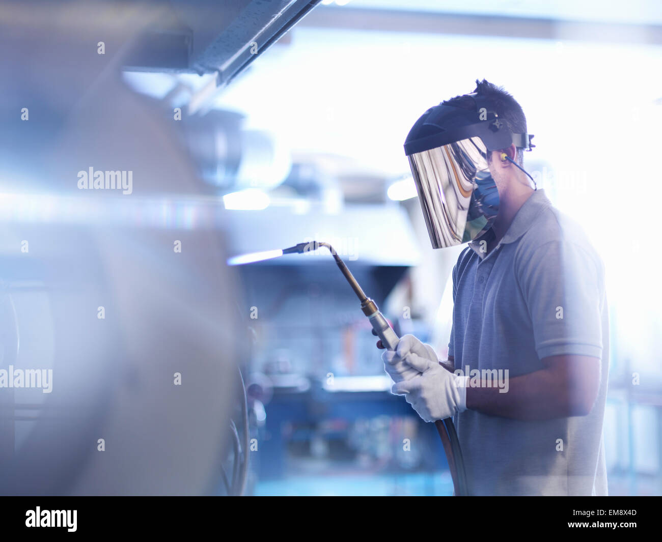 Apprentice glass blower wearing mask and using lance Stock Photo